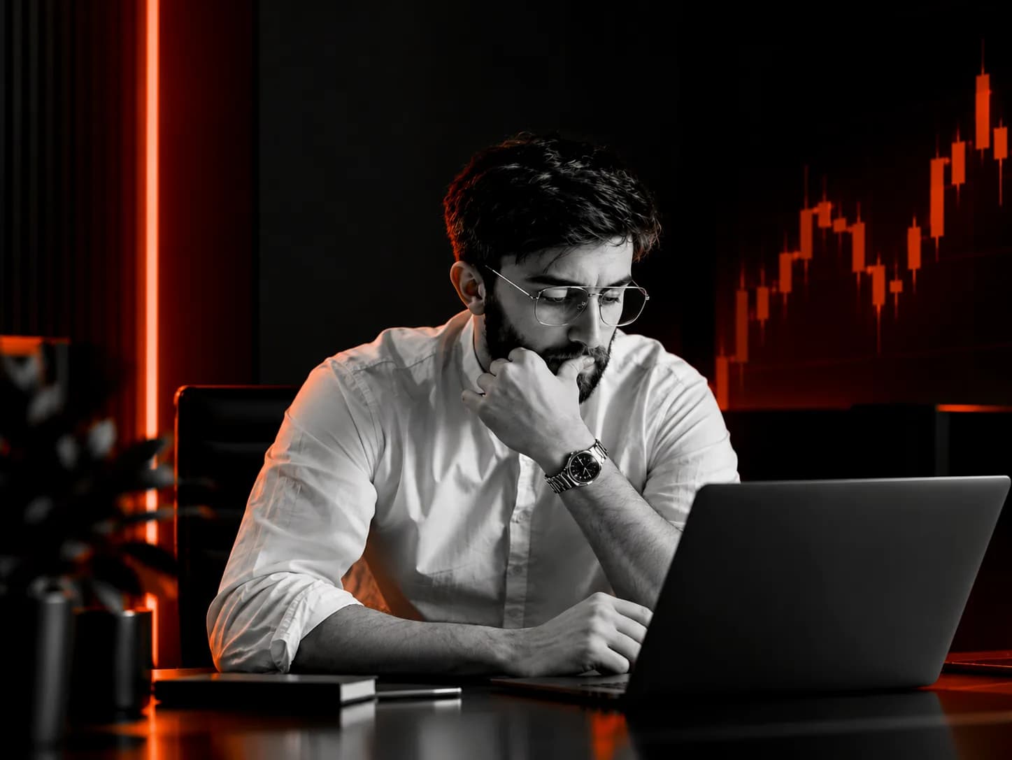 A trader thinking at a laptop, with a rising chart glowing behind him